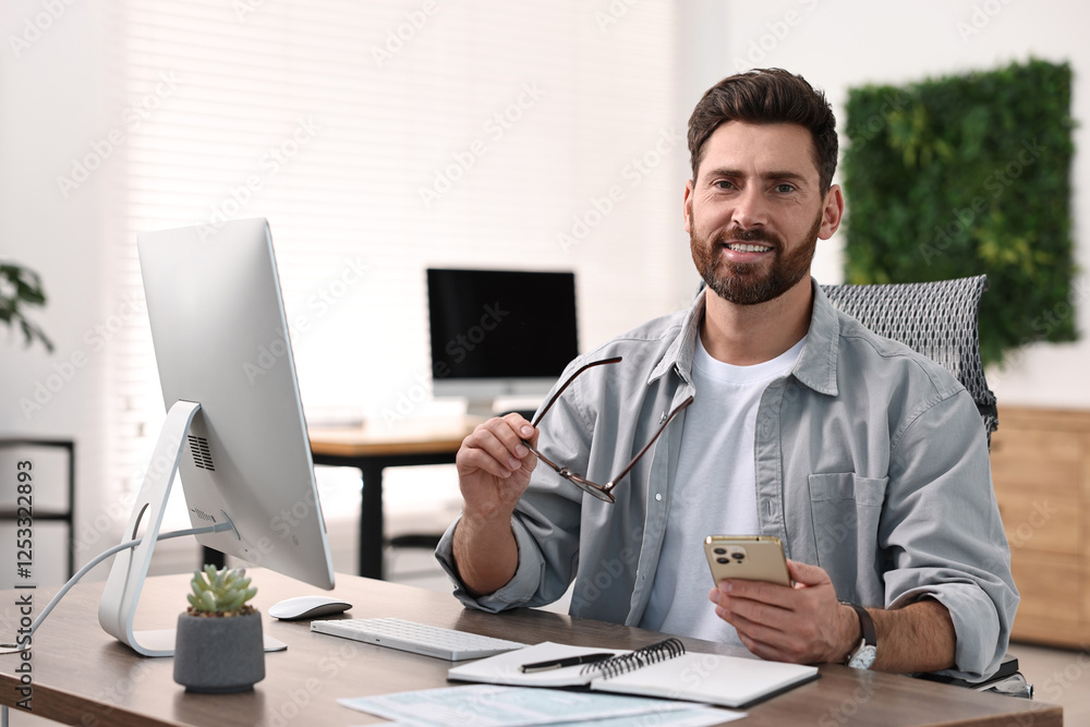 Poster man with smartphone working at table in office