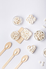 White pills and tablets in small plates on a white background, top view. Many vitamins, minerals and organic food supplements in forms of pills. Healthy lifestyle. Beautiful composition with pills.
