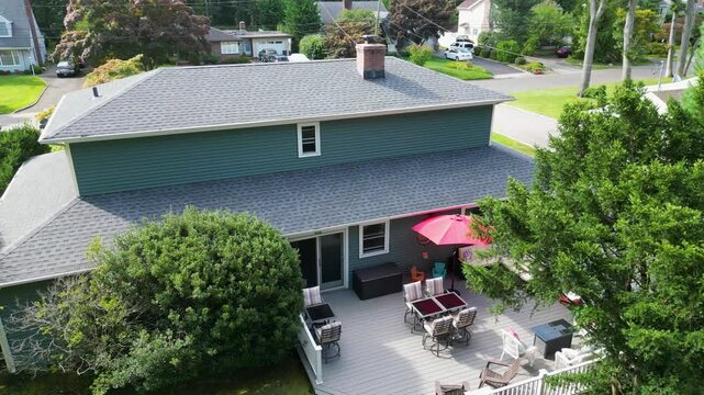 Explore a well-maintained backyard featuring cozy patio furniture and a vibrant red umbrella on a sunny day.