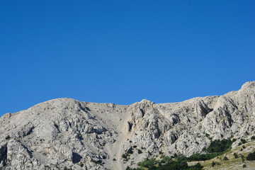 Imposing, rocky slopes of the mountains tower over the western part of Baska Bay on island Krk in...