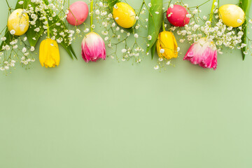Spring Easter background, multi-colored Easter eggs with tulips and gypsophila on a green background