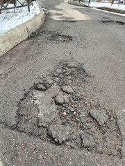 Damaged Asphalt Road with Multiple Potholes in Winter Setting