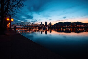 Fototapeta premium City skyline reflected on calm river at dusk