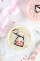Valentine’s Day-themed mini cake in a takeout box, surrounded by pink decorations.
