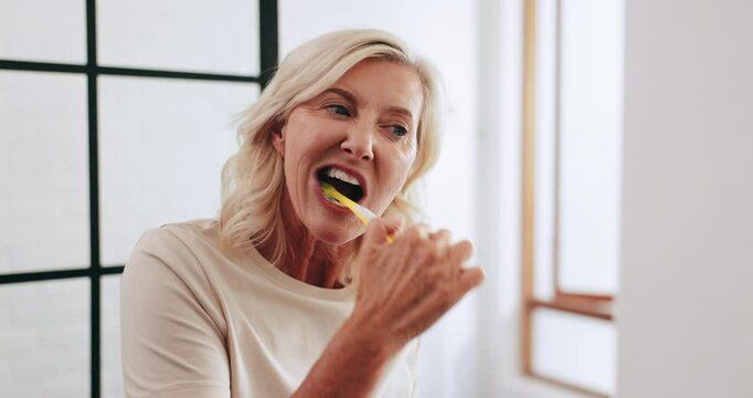 Bathroom, morning and mature woman brushing teeth for oral hygiene, fresh breath and getting ready. Health, wellness and senior person with toothbrush for dental care, cleaning and grooming in home