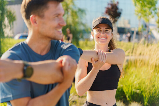 Group of friends stretching outdoors in a park during a sunny morning workout session