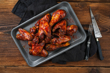 Authentical barbecue chicken wings and drumsticks with hot chili sauce as marinade served as top view in a rustic backing sheet with copy space