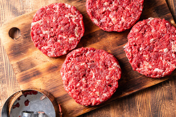 Homemade raw beef burger patties on a wooden board. Hamburger preparation. View from above.