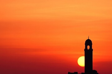 Silhouette of a historic tower during a vibrant sunset, showcasing warm orange tones and deep shadows against the colorful sky
