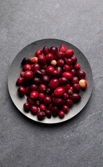 Overhead of a plate of cranberries and a pot full of whole cranberry