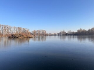Snow-covered lake with trees in the background, city