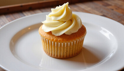 Golden cupcake with creamy frosting on white plate, dessert delight