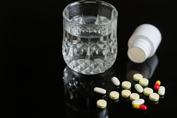 Pills and Water on Black Surface