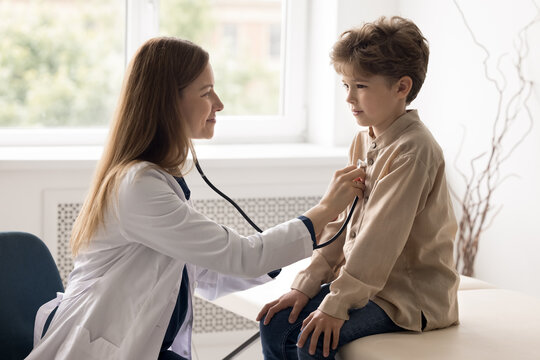 Timely screening examination. Professional female doctor pediatrician cardiologist checking up school age child patient health during regular meeting visit listen to heart beat rate using stethoscope
