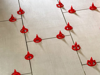 Red, plastic spacers between newly installed floor tile before grouting