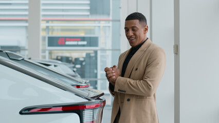 African American man guy male customer buyer dreaming buy rent vehicle in auto showroom pensive...