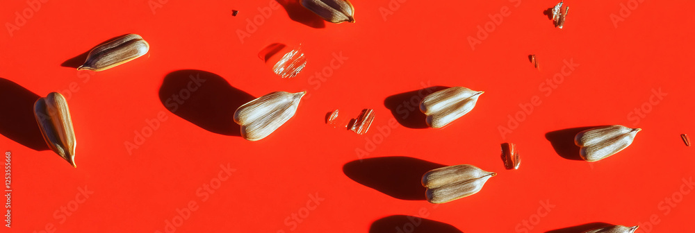Aufkleber scattering of sunflower seeds on bright red background with varied textures and sizes
