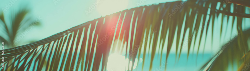 Poster view through palm leaves towards ocean with dappled sunlight creating a bright, tropical atmosphere