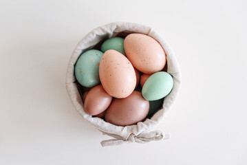 Basket with easter eggs on white table. Top view