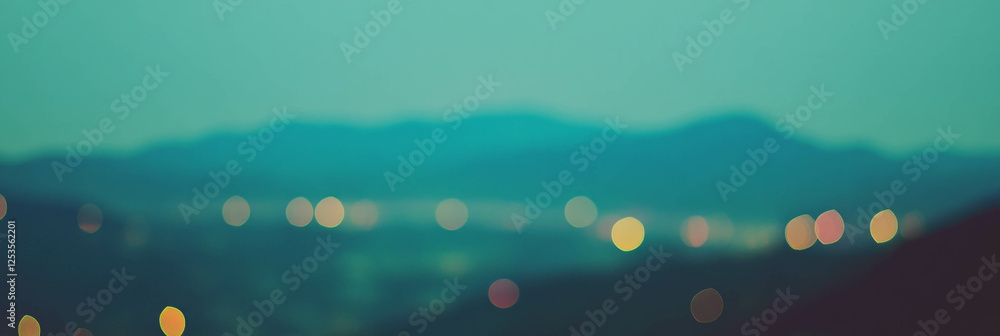 Aufkleber Blurred mountain range with distant lights creating a serene, atmospheric backdrop