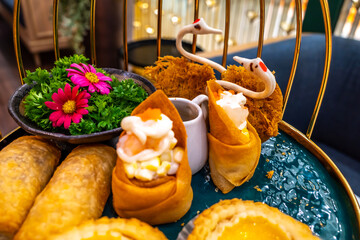 Assorted set in high tea set in luxury restaurant and tea room, dumpling, deep fried roll, custard pie, decorated in beautiful arrangements