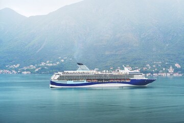 Ship sailing by green mountain and village