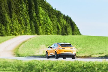 Yellow SUV Driving by Forest and Fields on a Sunny Day