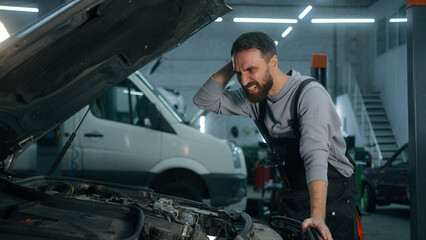 Confused shocked Caucasian guy man auto mechanic male repairman open hood bonnet fixing broken car...