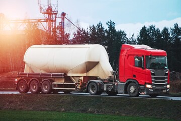 Large red truck hauling a white tank trailer