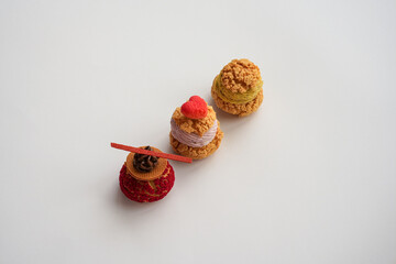 Three delicious cream puffs, one topped with a red heart, on a white plate, perfect for Valentine's...