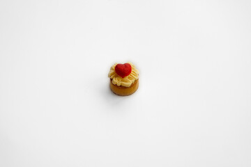Three delicious cream puffs, one topped with a red heart, on a white plate, perfect for Valentine's...