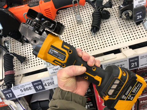 A customer holds a bolgar in his hand in a construction supermarket.