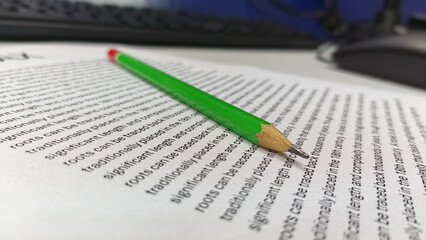 Green Pencil Resting on Text Document on Office Desk