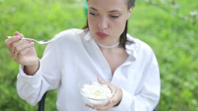 young woman eating cottage cheese in nature country house farm