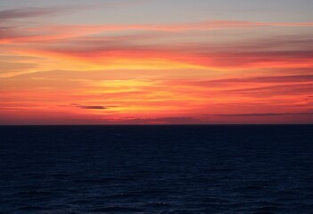 Obraz premium Stunning Ocean Sunset Bathed in Fiery Orange and Pink Colors