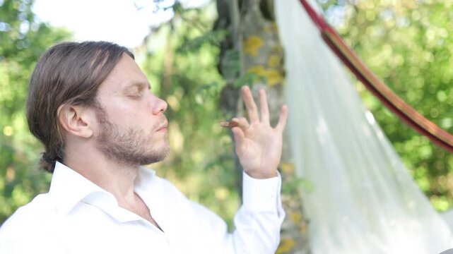 A man with long hair savors chocolate in the garden
