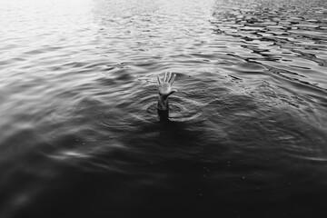 una mano sobresale en el agua pidiendo ayuda. 