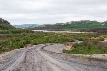 Winding gravel road leading to the Rybachy Peninsula in Murmansk region, Russia. Titovka River...