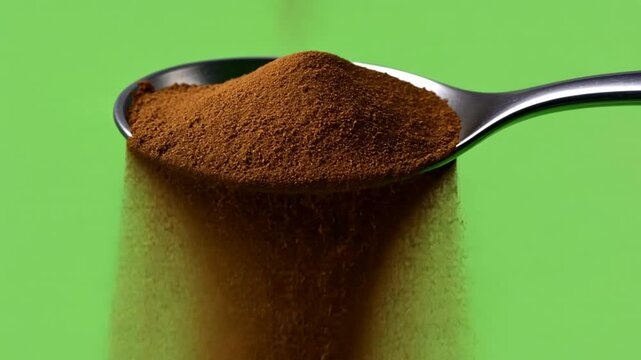 Instant Coffee in Spoon: A close-up image captures the moment instant coffee granules cascade from a silver spoon against a vibrant green backdrop.