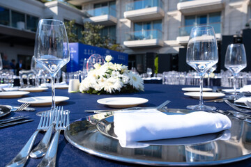 White flowers and glasses are placed on the event table. Cutlery is arranged neatly.