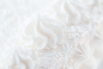 White blurred background. Close-up of intricate white decorations on festive cake, showcasing beautiful icing designs and details. Selective focus, defocus