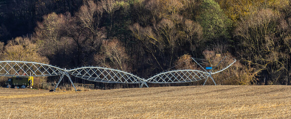 Unusual landscape showing twisted metal structure amidst barren field and trees during winter...