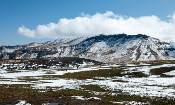 People in the distance below a winter snow-covered mountain at the top of Lichens Pass, Golden Gate Highlands National Park, southern Drakensberg - Powered by Adobe