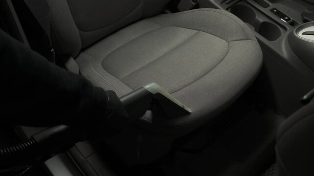 Car cleaner is extracting dirt from car seat using dry cleaning extractor machine 4k video. Cleaning textile seats in car interior using extractor machine for dry clean.