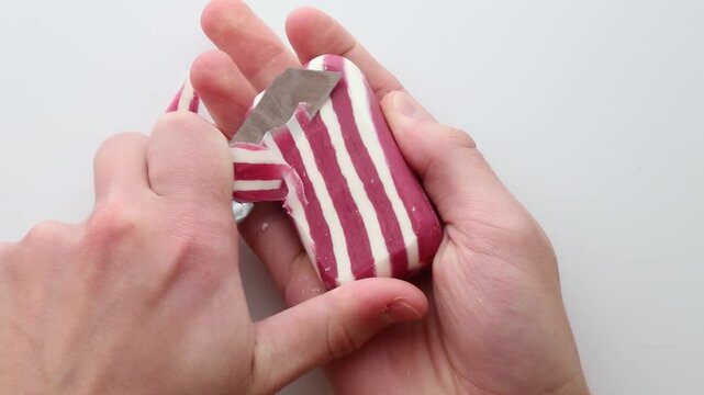 Close-up of hands slicing red-striped soap with a knife, creating thin curls and smooth textures, evoking satisfaction and focus. Ideal for ASMR content and relaxation themes. Part 1 of 2