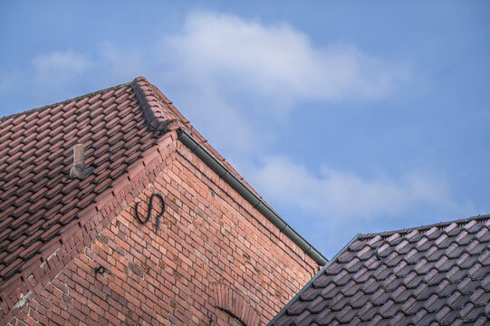 Historisches Backsteingeb&auml;ude mit Walmdach Giebelseite mit Maueranker vor blauem Himmel mit Wolken in Pliezhausen
