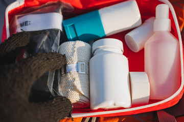 A person is carefully holding a bag filled with various bandages and bottles that are neatly organized inside a wellprepared first aid kit for emergencies or medical situations