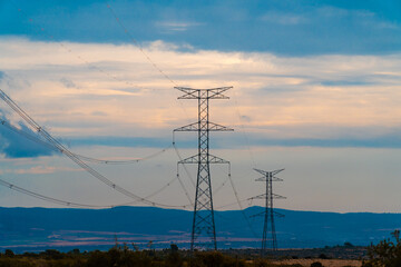 High voltage pylons in a field, on a winter morning with cloudy sky.