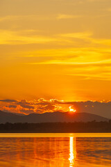 Landscape of mountains and lake at sunset and clouds reflected in the water.