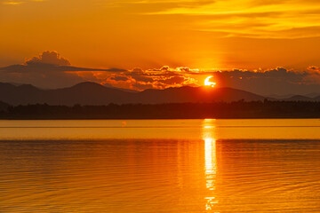 Landscape of mountains and lake at sunset and clouds reflected in the water.